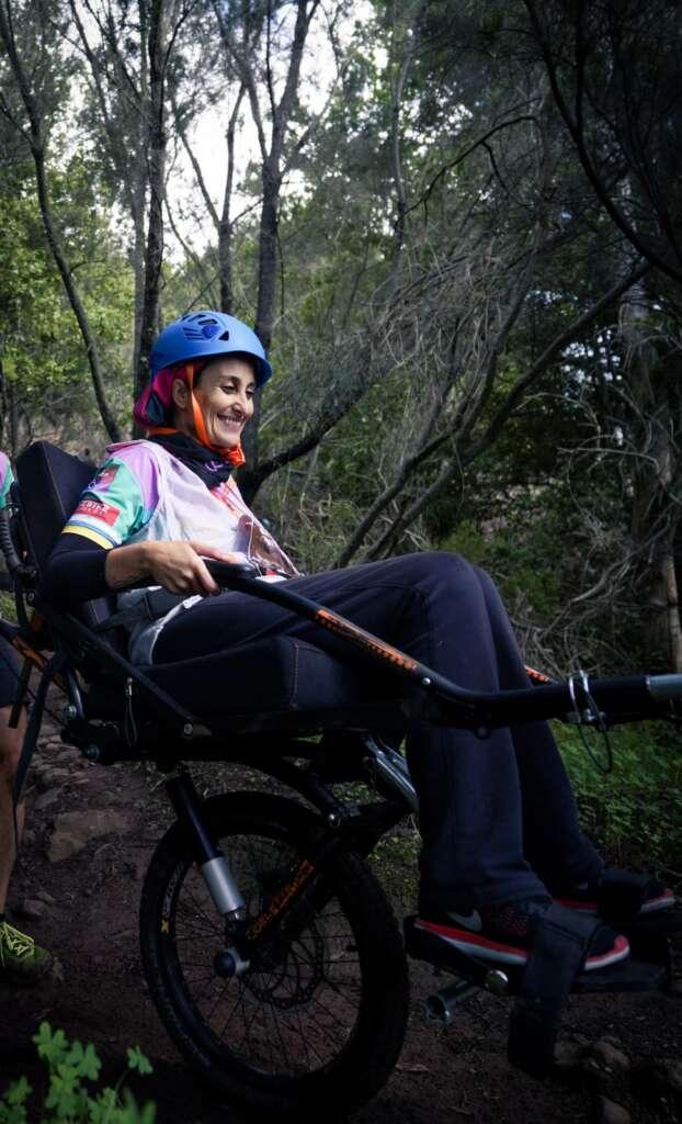 Descripción de la foto: Isabel Elvira en la silla joëlette, con casco y muy sonriente.