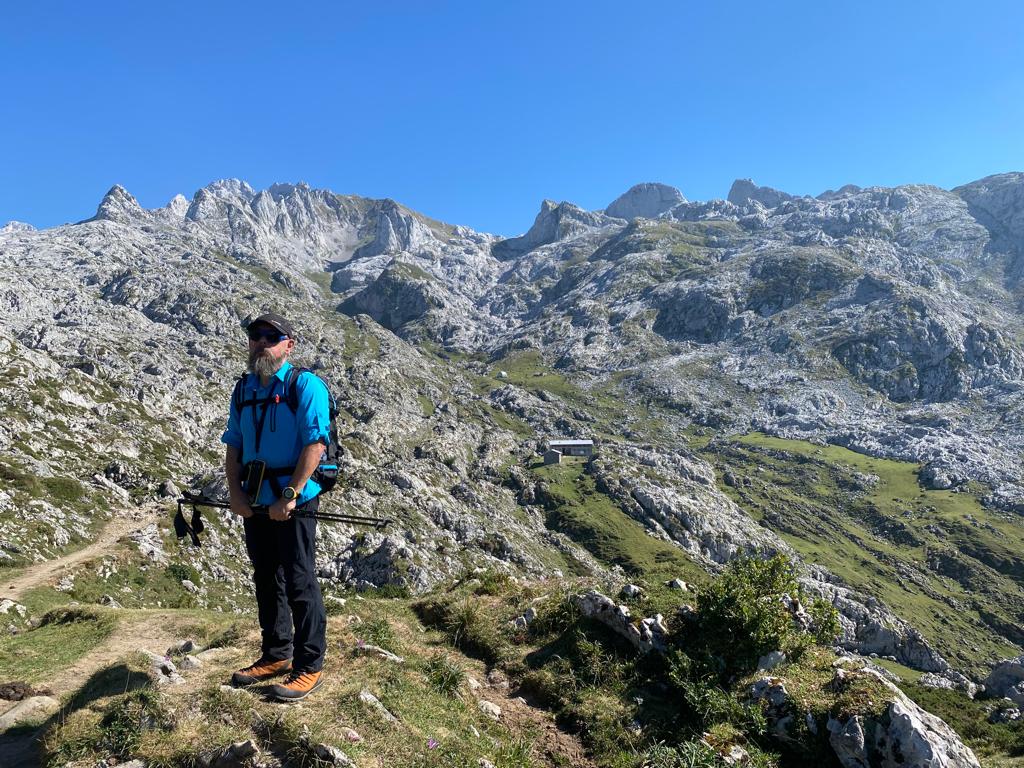 Descripción de foto de portada: El autor en el Macizo Occidental de Picos de Europa. Montañero con una vista de montañas y refugio al fondo.