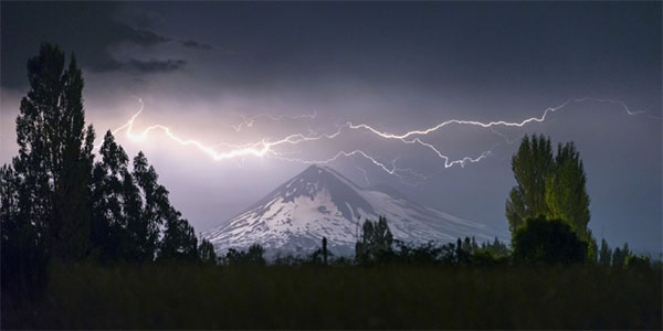 Imagen de portada: En un paisaje oscuro, se ve una montaña nevada ye iluminada por un rayo.