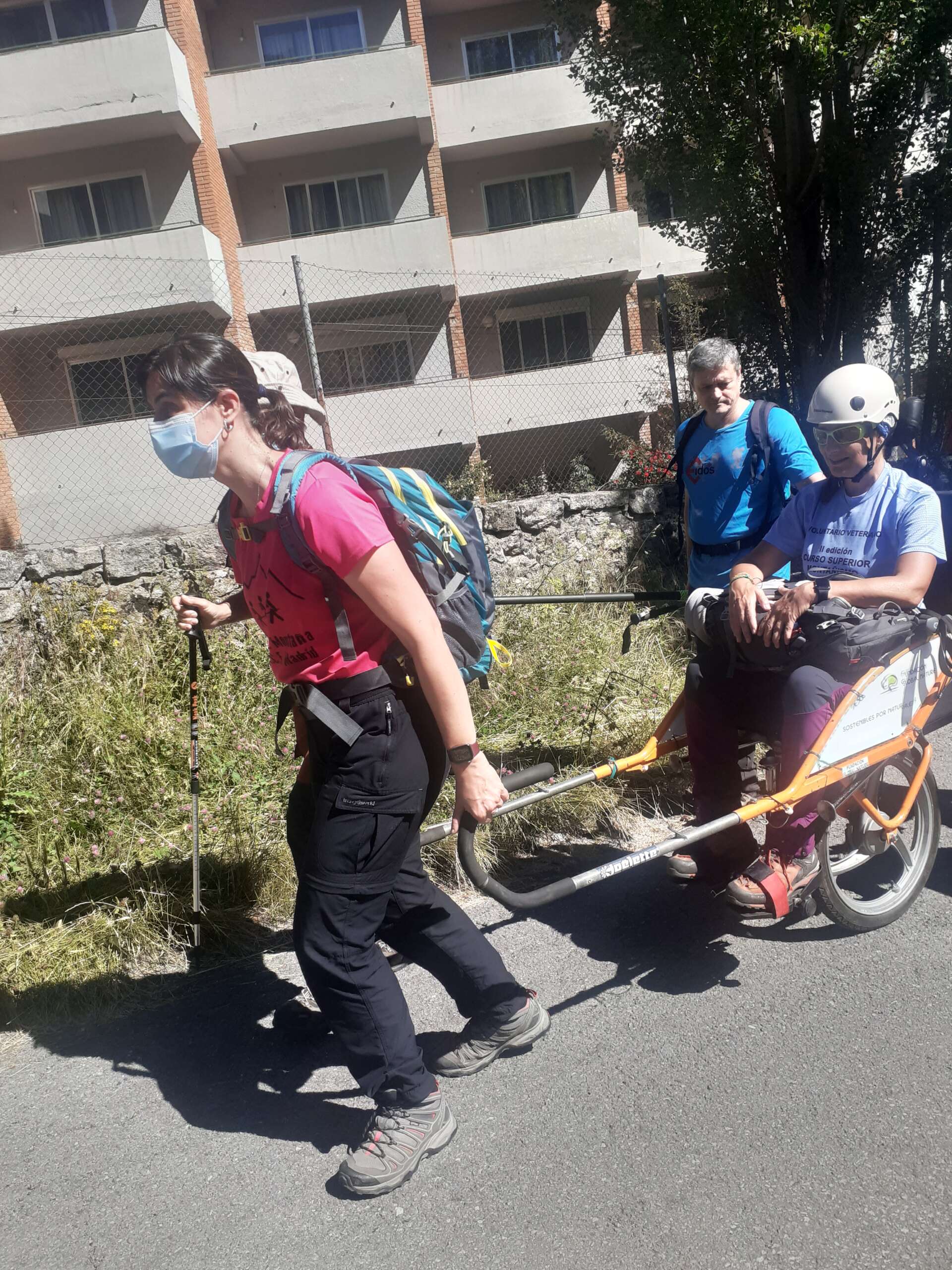 Imagen de un curso de conducción Silla Jöulette. Se ven tres personas, una en la silla, y una chica delante llevando la silla. También se ve en la imagen una persona acompañante al lado del ocupante en la silla