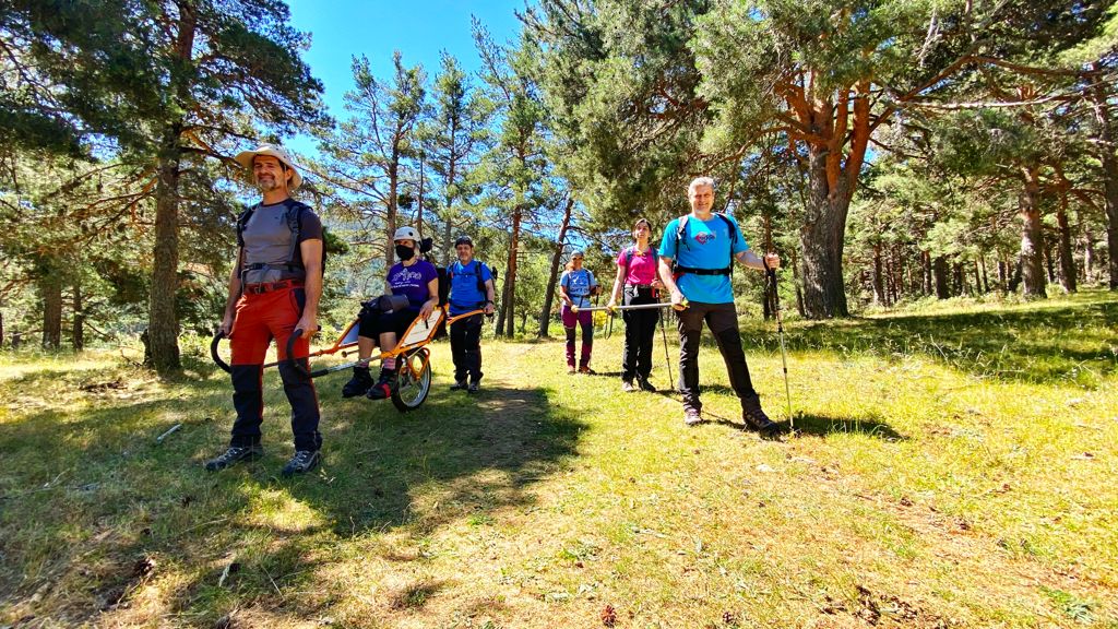 Imagen de varias personas en el campo. En dos grupos, unos llevando una silla Jöulette, y otros con barra direccional