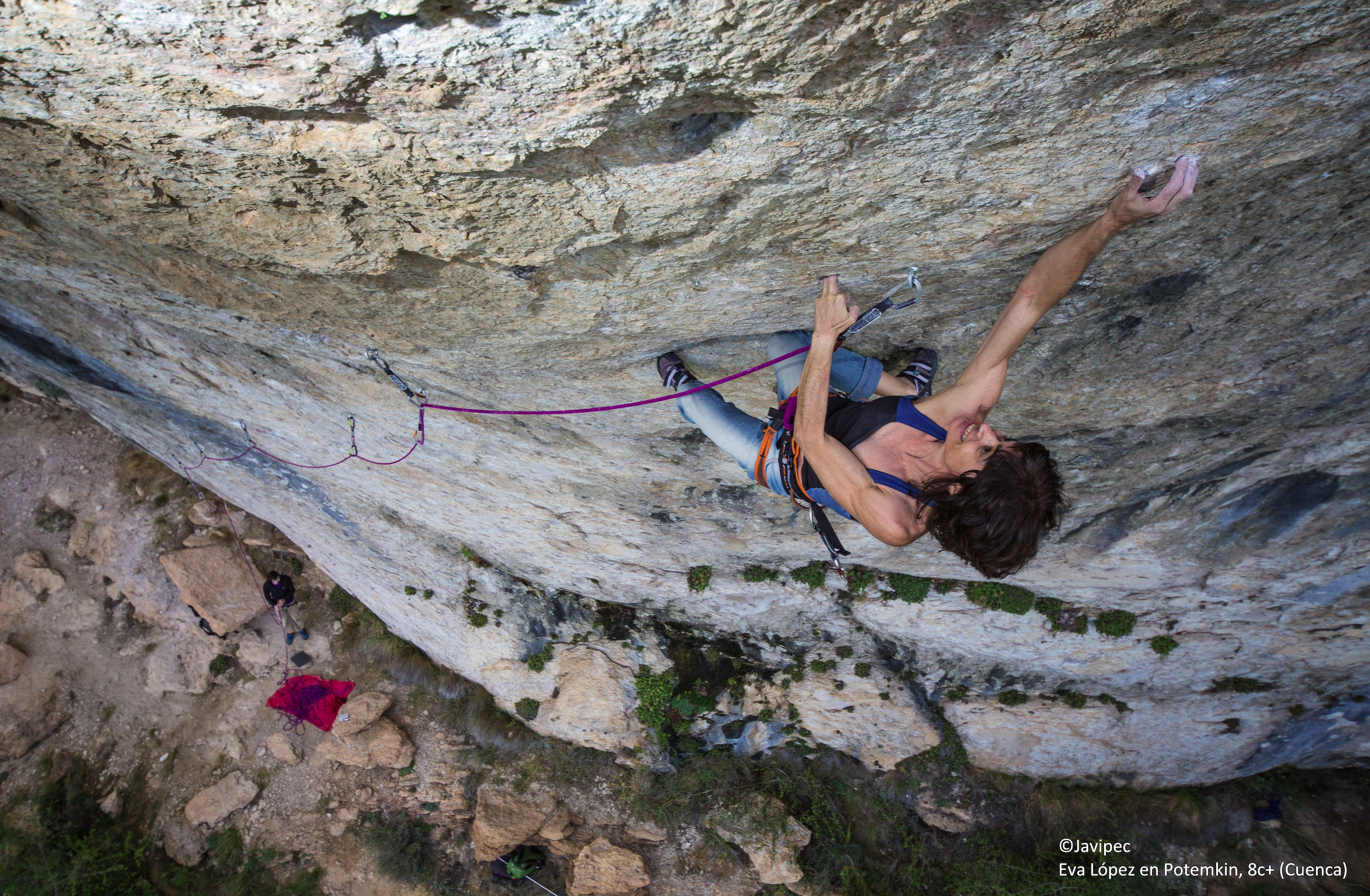 Foto tomada desde arriba en la vía Potemkin 8c+ en Cuenca. Eva escala de primera en una pared rocosa con cierto desplome mientras que abajo a considerable distancia se ve la silueta de una persona que la asegura.