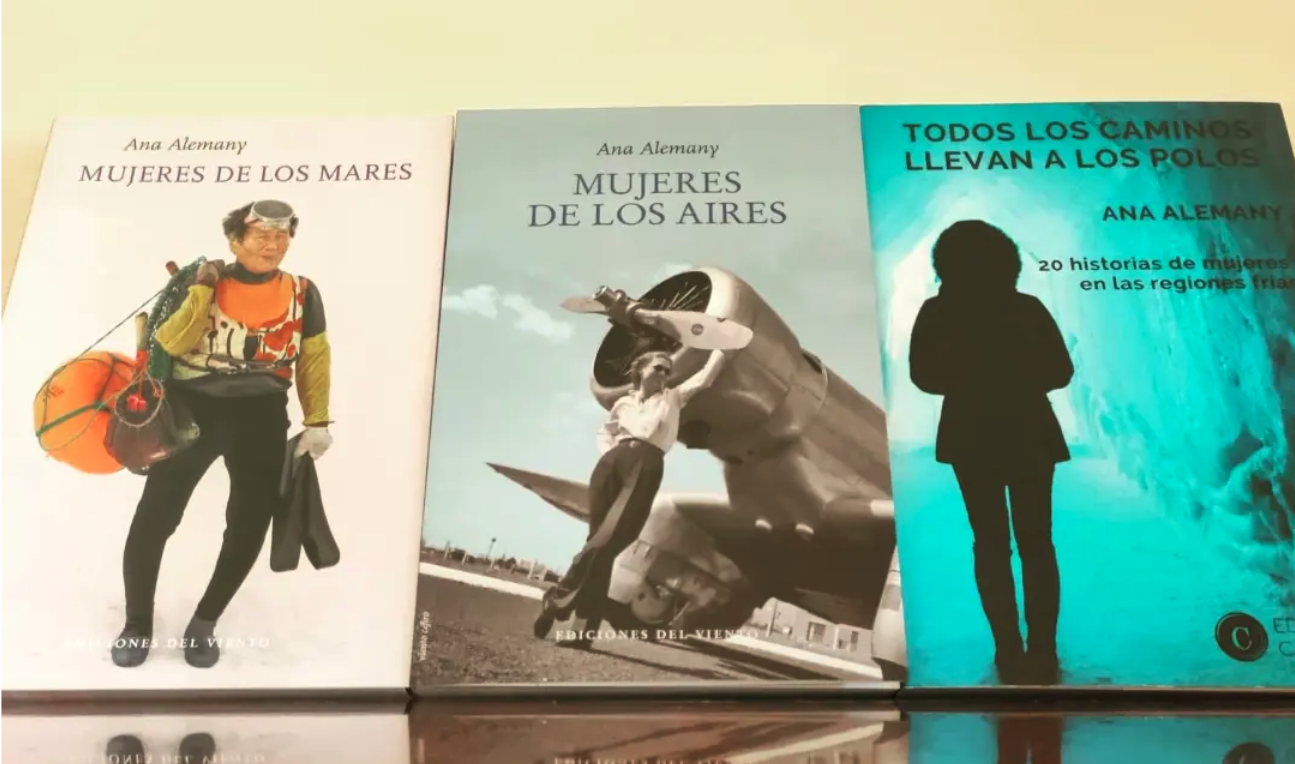 La foto muestra una copia de Mujeres de los Mares a la izquierda, otra de Mujeres de los Aires en el centro y a la derecha una copia de Todos los caminos llevan a los Polos. En la portada de cada uno de ellos hay una ilustración de una mujer con traje de buzo, frente a la hélice de un avión y con ropa de abrigo apropiada para el Polo respectivamente.