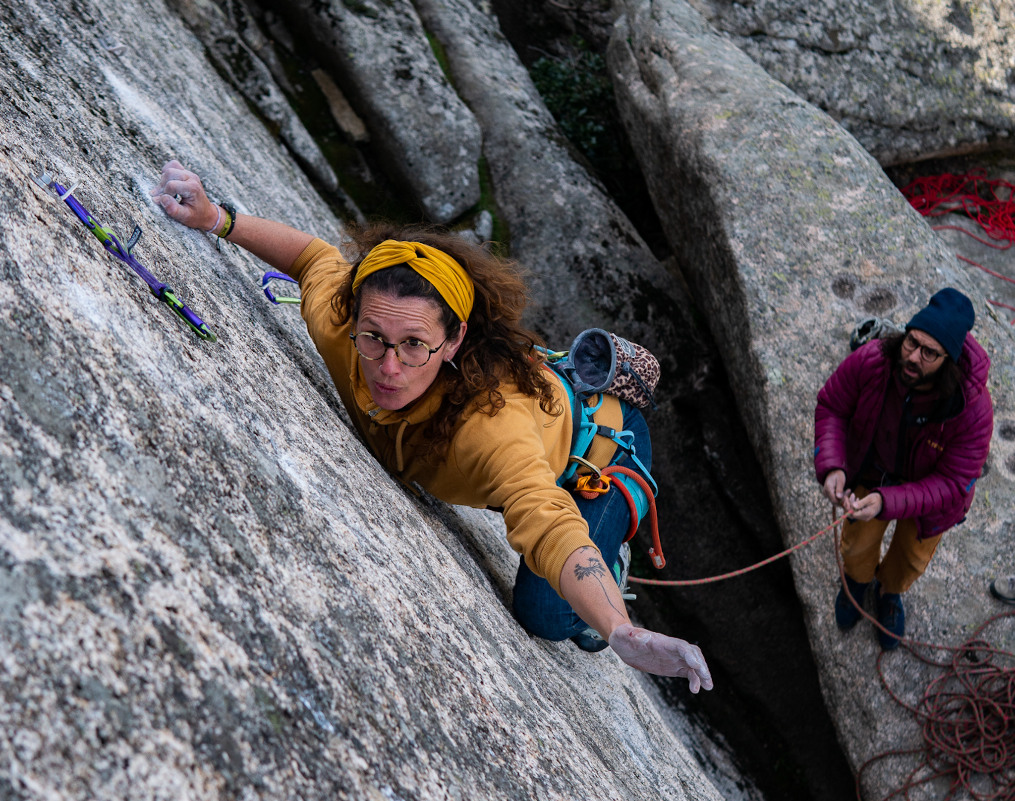 La foto está tomada desde arriba y se ve a Roser ascendiendo por la vía Inuit en La Pedriza mientras que abajo al fondo su compañero la asegura.