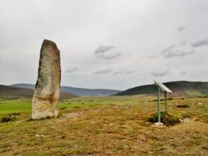 Fotografía que presenta uno de los menhires del recorrido, junto con un panel informativo.