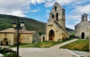 Fotografía que presenta el espacio urbano central de Aldea de Ebro, con los edificios de piedra de la iglesia y la espadaña exenta.