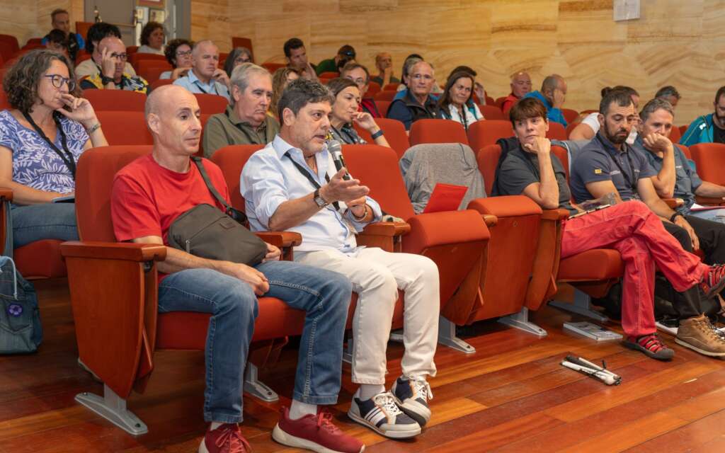 7. Imagen de asistentes donde Francisco Javier Bueno con micrófono en mano está formulando una pregunta