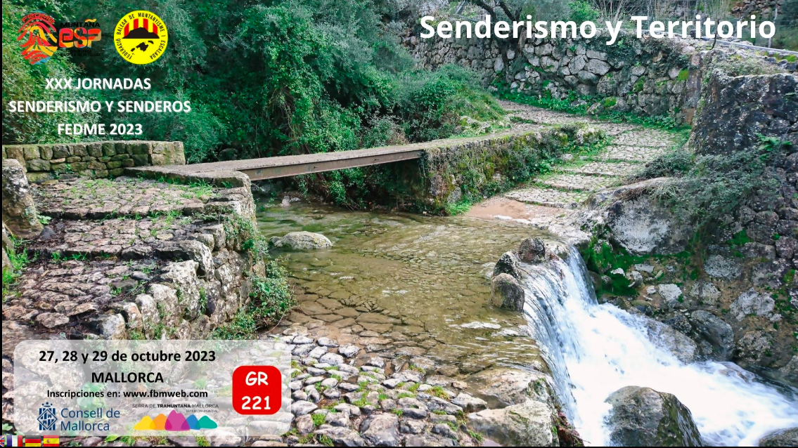 Cartel a todo color que presenta el punto en el que el sendero GR® 221, empedrado y flanqueado por muros de piedra seca, cruza un barranco con agua, tanto por una palanca como por un vado. Sobre impresionado aparece el lema de las mismas “Senderismo y Territorio” los logos de la FEDME y de la FBME y una cartela con las fechas, la web de referencia y el logo del Consell de Mallorca.
