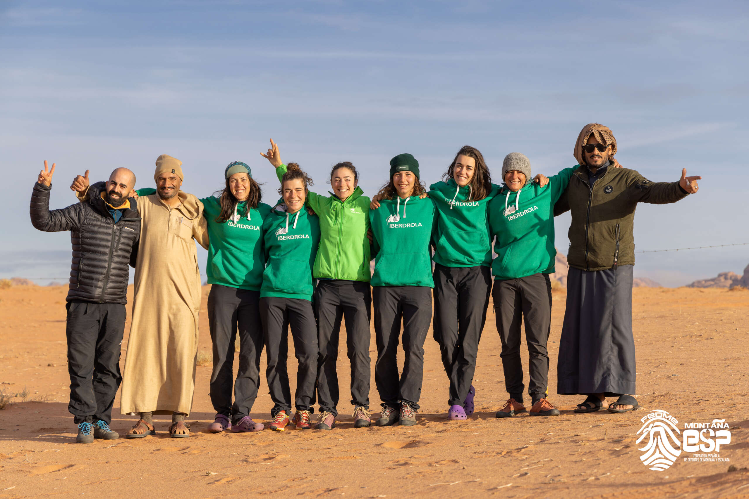 Amaia Agirre aparece en el centro de la foto, con brazo derecho levantado apuntando al cielo, abrazando por uno y otro lado a sus compañeras del equipo de alpinismo femenino de la FEDME, y en los extremos dos hombres de Arabia y el productor del documental Juan Miguel Ponce. Se encuentran en uno de los desiertos en su expedición de Abriendo Camino en Jordania y Arabia Saudí.