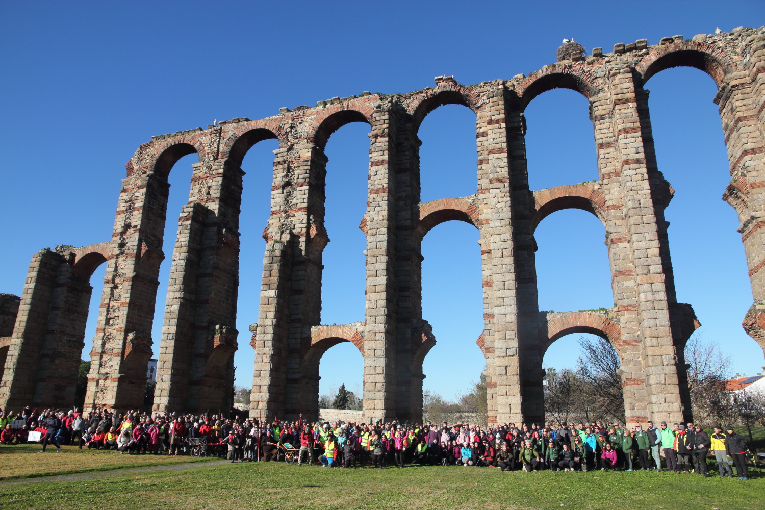 Fotografía en color que presenta a una grupo de andarines, bajo el acueducto de los Milagros de Mérida (Cáceres,) perteneciente a la ruta Monumental de Octavio Augusto de 2023