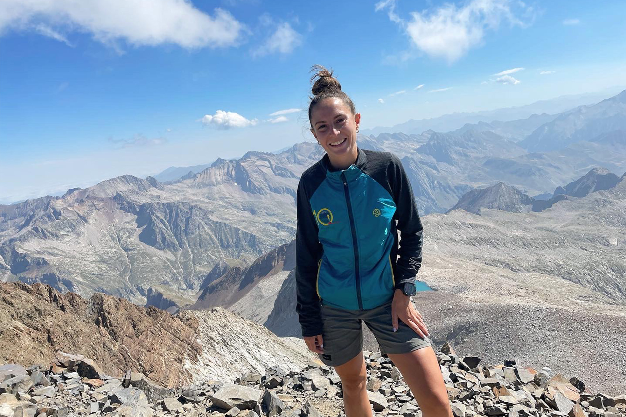 Clara se encuentra en la cima del Pico Posets (Aragón) muy sonriente y de fondo todo un paisaje de bellas montañas de roca
